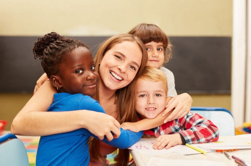 Glückliche Kinder umarmen ihre Erzieherin